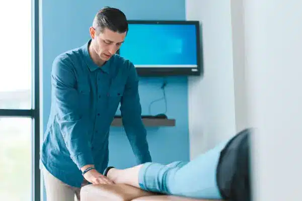 chiropractor giving leg massage to a man in clinic
